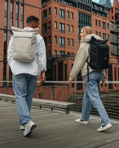 Zwei Personen mit Rucksäcken gehen durch eine Stadt.